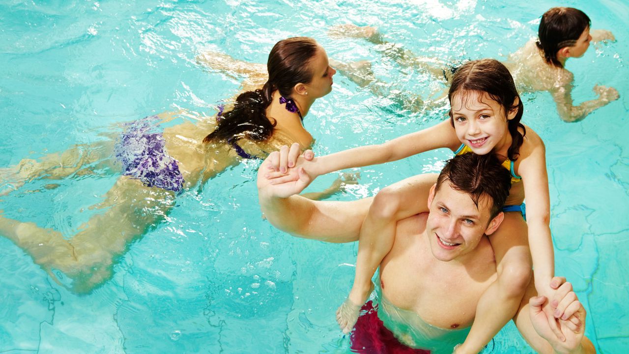 Ung mand med pige på skulderen i vandet